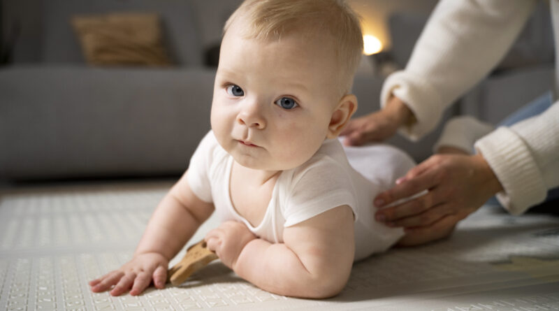 Kapan Bayi Mulai Tummy Time dan Durasi Idealnya? Gambar seorang bayi yang gembira sedang melakukan tummy time di atas karpet dengan kepala terangkat.