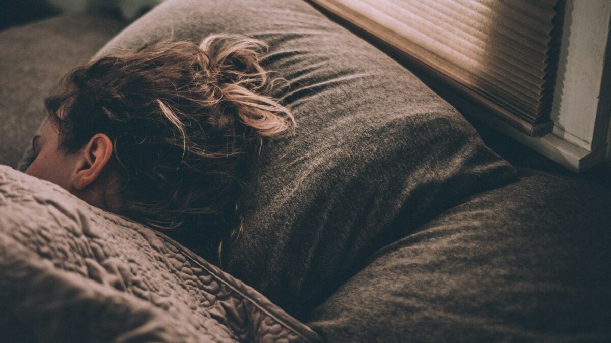 Seseorang tidur nyenyak di kamar yang redup, ilustrasi cara cepat tidur